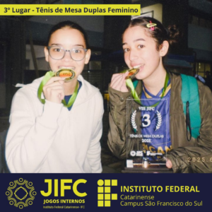 Duas alunas do IFC aparecem sorrindo, cada uma segurando uma medalha de bronze na boca. À frente delas está o troféu do 3º lugar em Tênis de Mesa Duplas Feminino – VIII JIFC 2025. Ambas usam o uniforme azul com o nome "Canaã Engenharia". A estudante à esquerda está com um casaco branco e óculos, enquanto a da direita usa um casaco verde e presilhas coloridas no cabelo. A imagem foi tirada em ambiente coberto. No topo, há uma faixa com o texto “3º Lugar – Tênis de Mesa Duplas Feminino”. Na parte inferior, os logotipos do JIFC e do IFC Campus São Francisco do Sul.