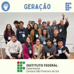 Foto colorida de um grupo com 19 pessoas, entre estudantes e servidores do Instituto Federal Catarinense – Campus São Francisco do Sul. Todos estão sorrindo, usando crachás e roupas de frio. A foto foi tirada em um ambiente interno, durante o evento de apresentação das propostas.
Na parte superior da imagem, há um banner com a logomarca do Grêmio Estudantil Geração. Na parte inferior, aparece o logotipo do Instituto Federal Catarinense – Campus São Francisco do Sul.