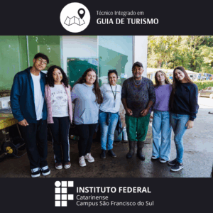Foto em ambiente externo, diante de uma parede verde. Seis pessoas posam sorrindo para a câmera. São cinco estudantes jovens e um homem da comunidade local, vestido com camiseta, colar artesanal e botas de borracha. Um dos estudantes veste blusa clara com a marca do Instituto Federal. No topo, está escrito: “Técnico Integrado em Guia de Turismo” com ícone de mapa e marcador. Na parte inferior, está a logomarca do Instituto Federal Catarinense – Campus São Francisco do Sul.