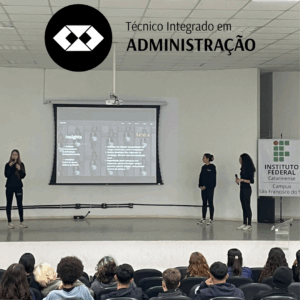 Auditório do IFC Campus São Francisco do Sul, com público sentado assistindo à apresentação de três alunas no palco. Elas usam roupas escuras e seguram microfones. Ao fundo, há uma tela de projeção com o slide “Insights”, com tópicos e imagens de pessoas em preto e branco. No canto direito está um banner vertical do IFC. No canto superior esquerdo da imagem há um círculo preto com o logotipo do curso técnico em Administração e a frase “Técnico Integrado em Administração”.