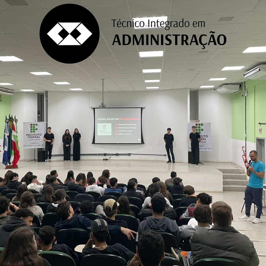 Auditório do IFC cheio de estudantes assistindo à apresentação de cinco alunos no palco. Quatro deles estão alinhados próximos à tela de projeção, vestindo roupas escuras. O quinto está mais à direita, também de preto. A projeção mostra o título “Arena Spartan” e uma lista de tópicos. Um professor em camiseta azul e calça esportiva segura um microfone e parece interagir com os alunos. No canto superior esquerdo há novamente o círculo preto com o logotipo do curso e o nome “Técnico Integrado em Administração”.